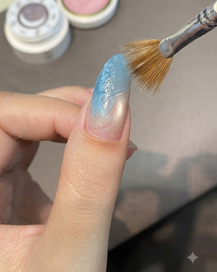 A striping brush sweeping diagonally across wet sculpting gel on a blue gradient nail to form raised ridges.