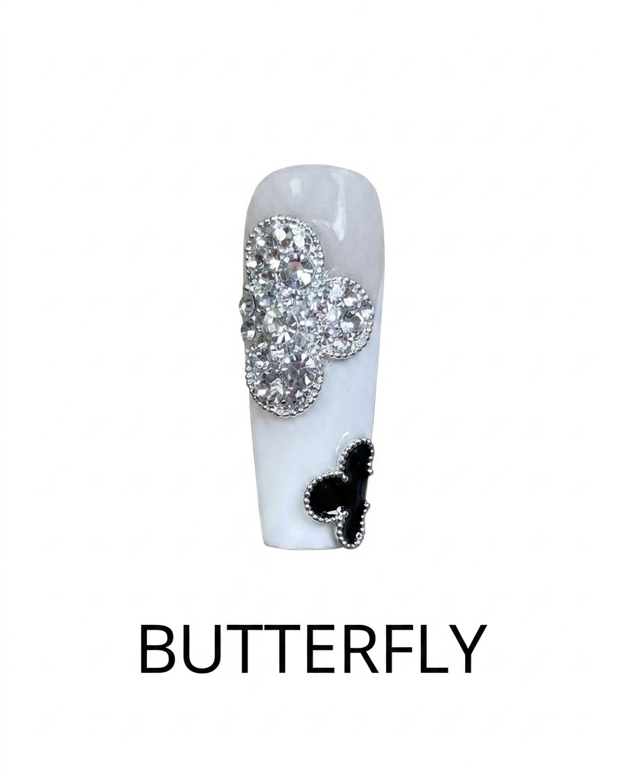 A close-up view of a finished nail design featuring a silver glitter rhinestone clover and a black clover accent.
