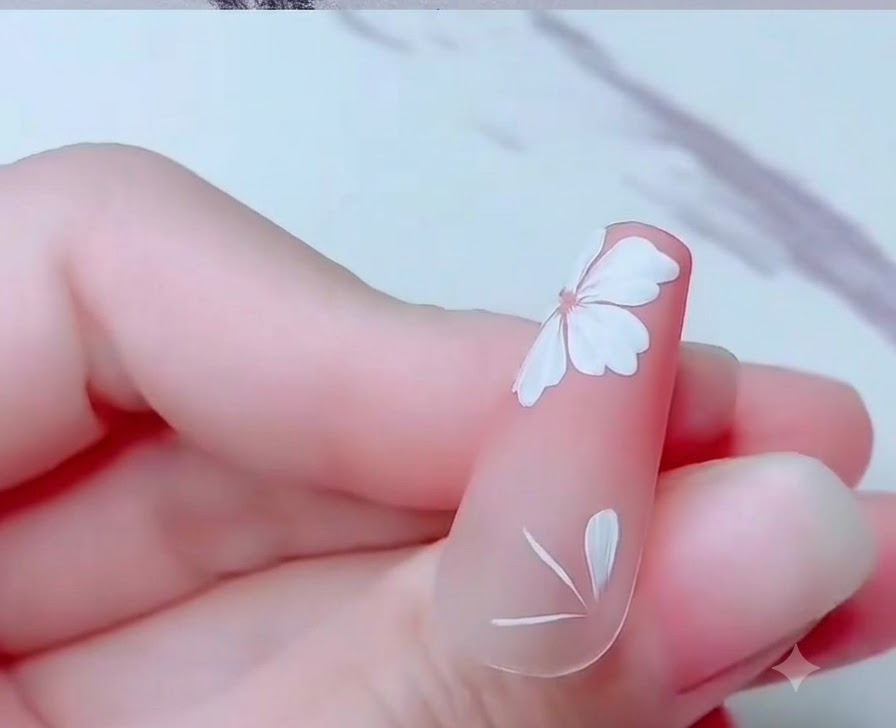 A close-up of a nail showing partial white cherry blossom petals painted near the bottom edge.
