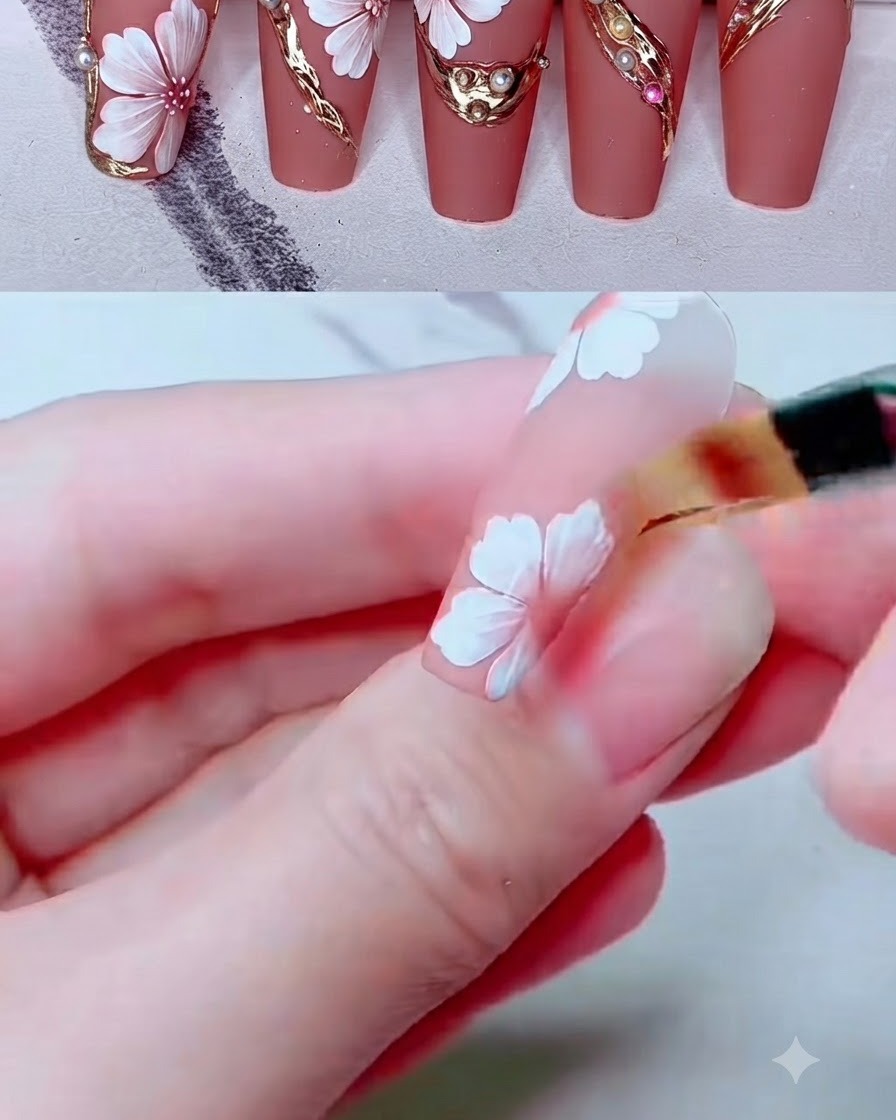 A small shading brush blending pink color on white painted flower petals on a nail.