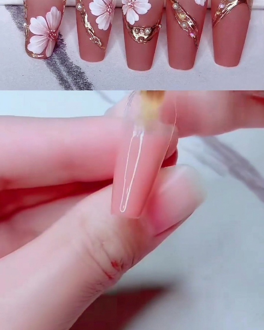 A fine nail art tool placing small white pearl beads onto the decorated nail surface.