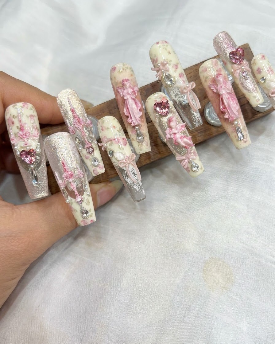 A sponge applicator dabbing pink blush gel onto the tip of a manicured nail.