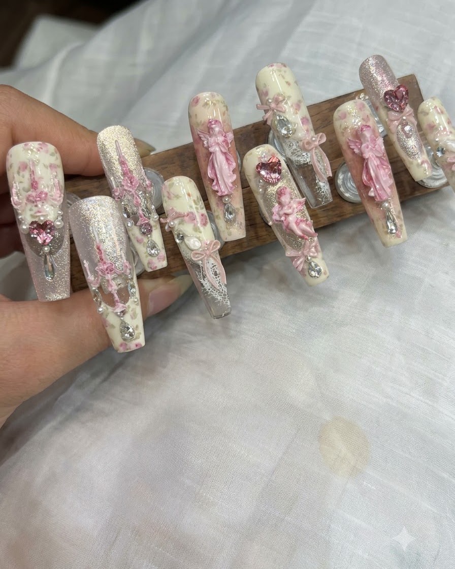 A fine detail brush applying tiny specks of glitter gel to the center of a decorated nail.