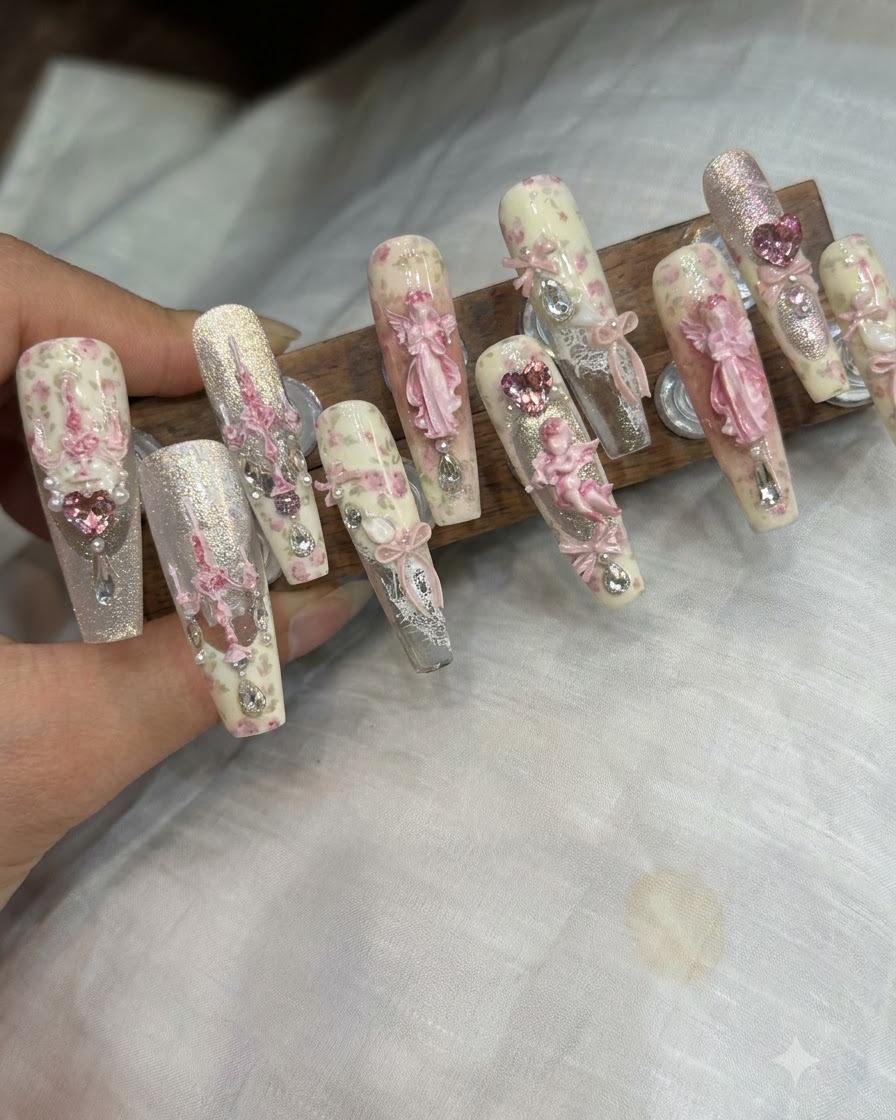 A pair of tweezers placing a 3D ribbon charm and rhinestones onto a finished nail.