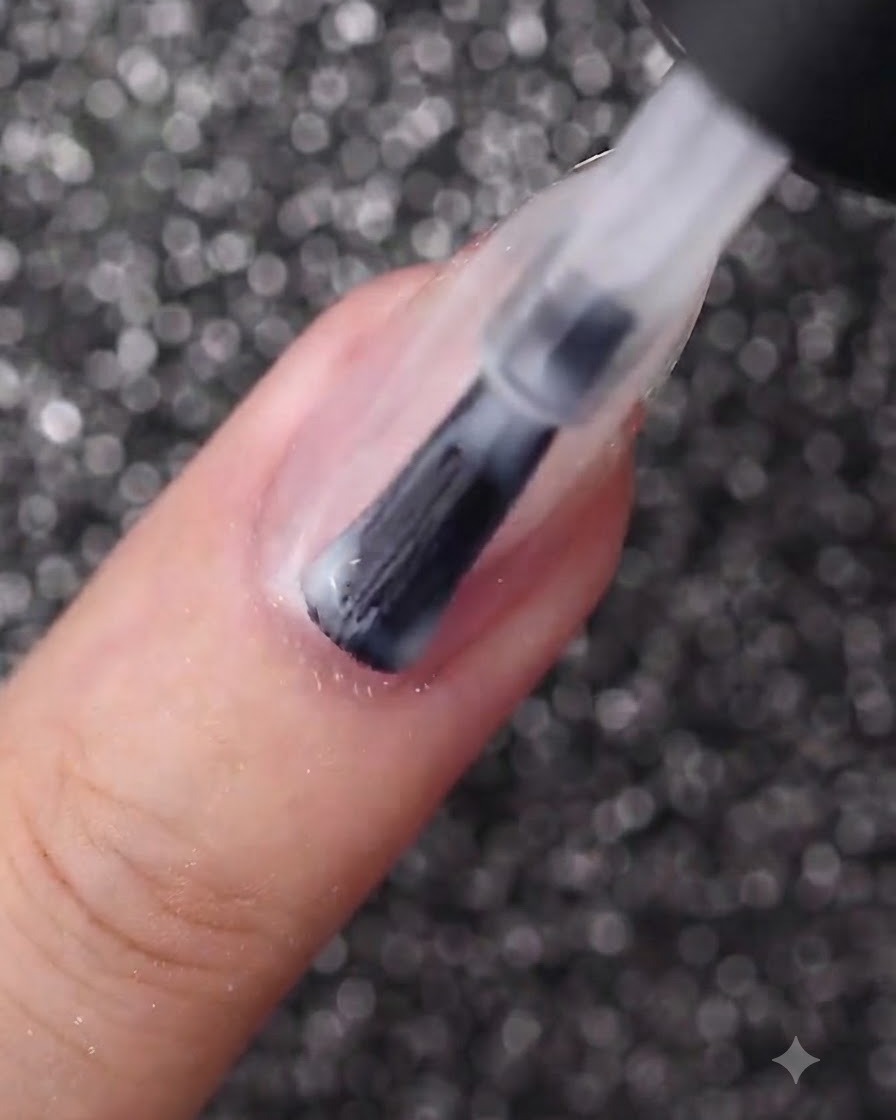 A nail brush applying a smooth layer of milky white gel polish onto an oval-shaped fingernail.