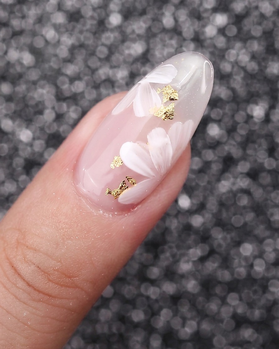 A close-up of white painted flower petals overlapping each other over a gel nail background.