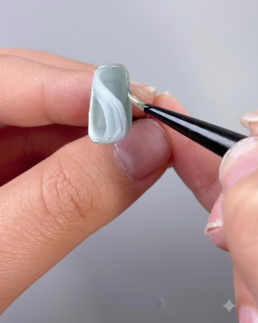 A fine detailing brush applying texture sculpting gel along the edge of a nail.
