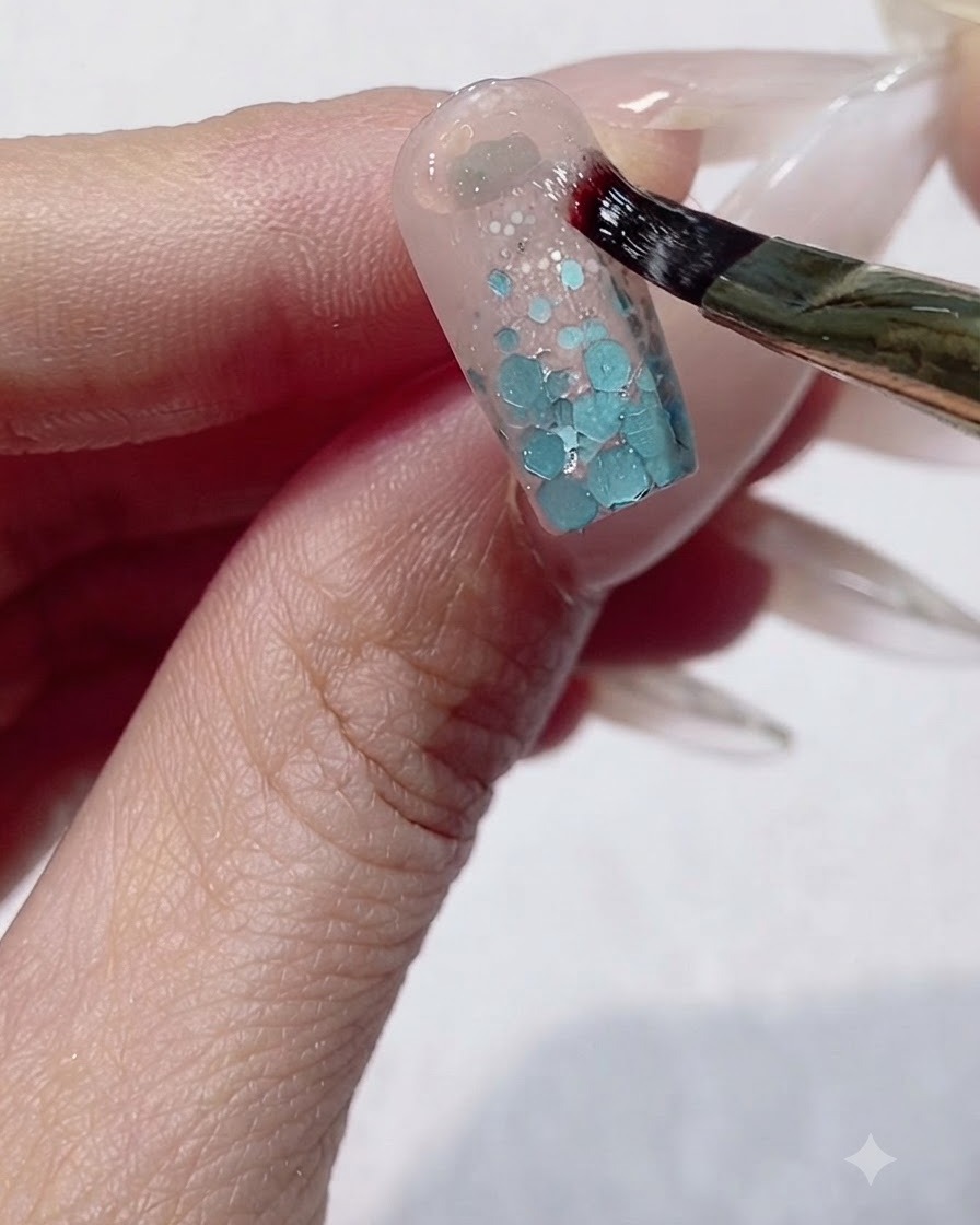 A fine brush applying thick sculpting gel in a U-shape around the cuticle area of a nail.