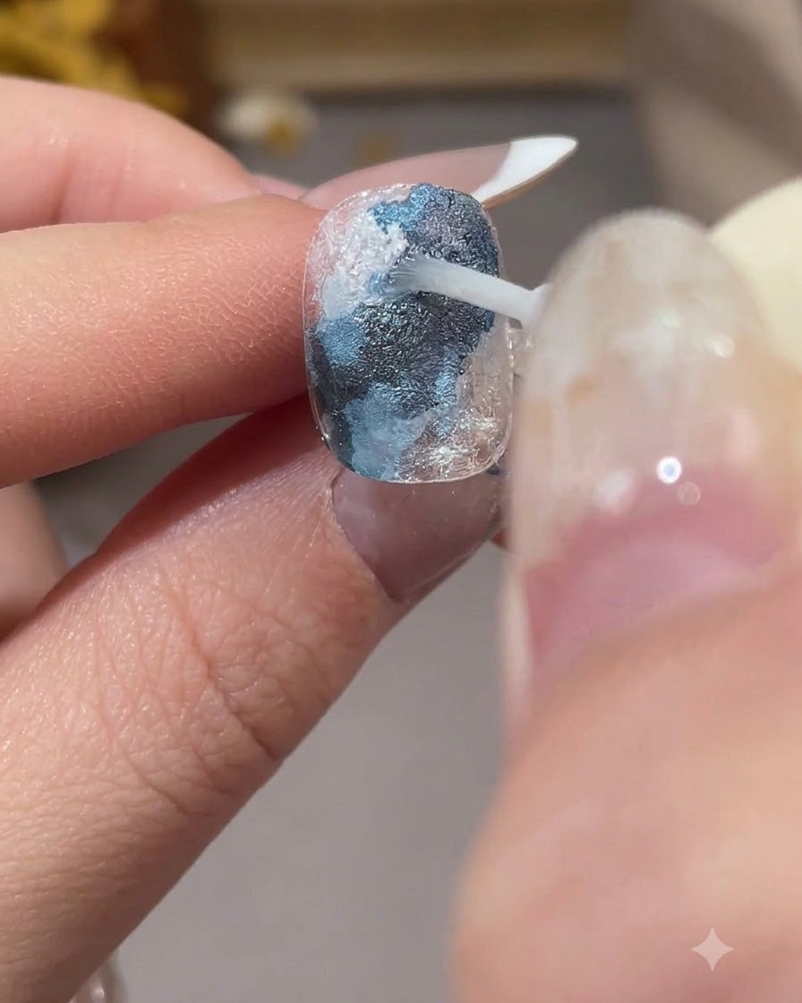A brush applying transparent smudging liquid over white sections to blend the colors.