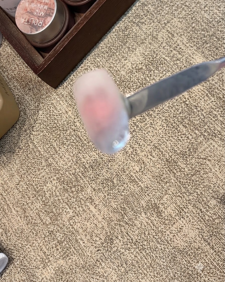 A nail curing under a handheld UV/LED lamp focusing on the freshly painted 3D clear tip detail.