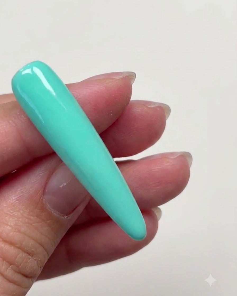 A long stiletto nail extension completely covered in a smooth layer of mint green color gel.