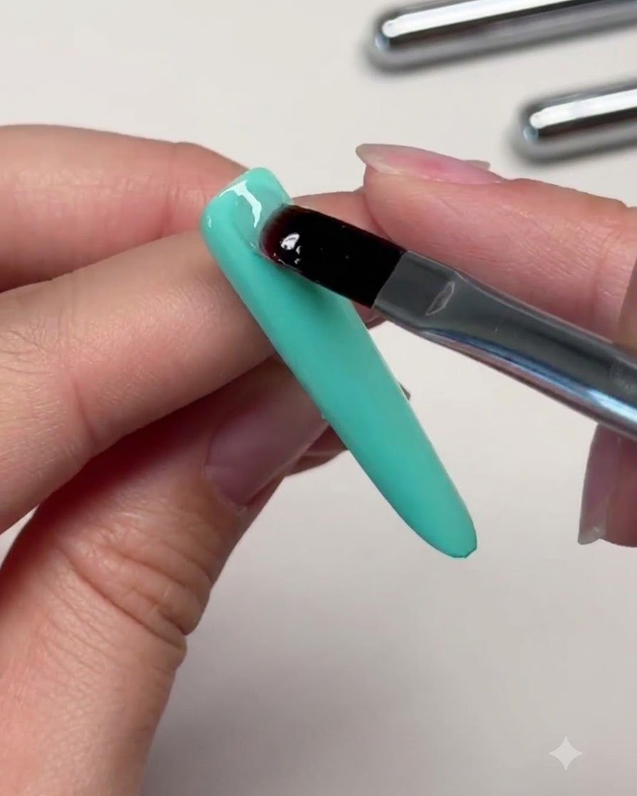 A brush placing a clear bead of reinforcing gel onto the upper section of a mint green nail to build an apex.