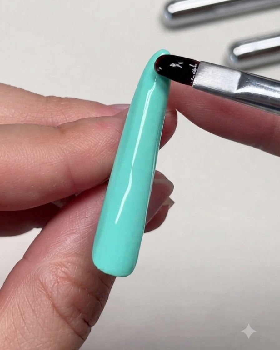 A close-up view of a brush leveling reinforcing gel near the tip of a long nail extension.