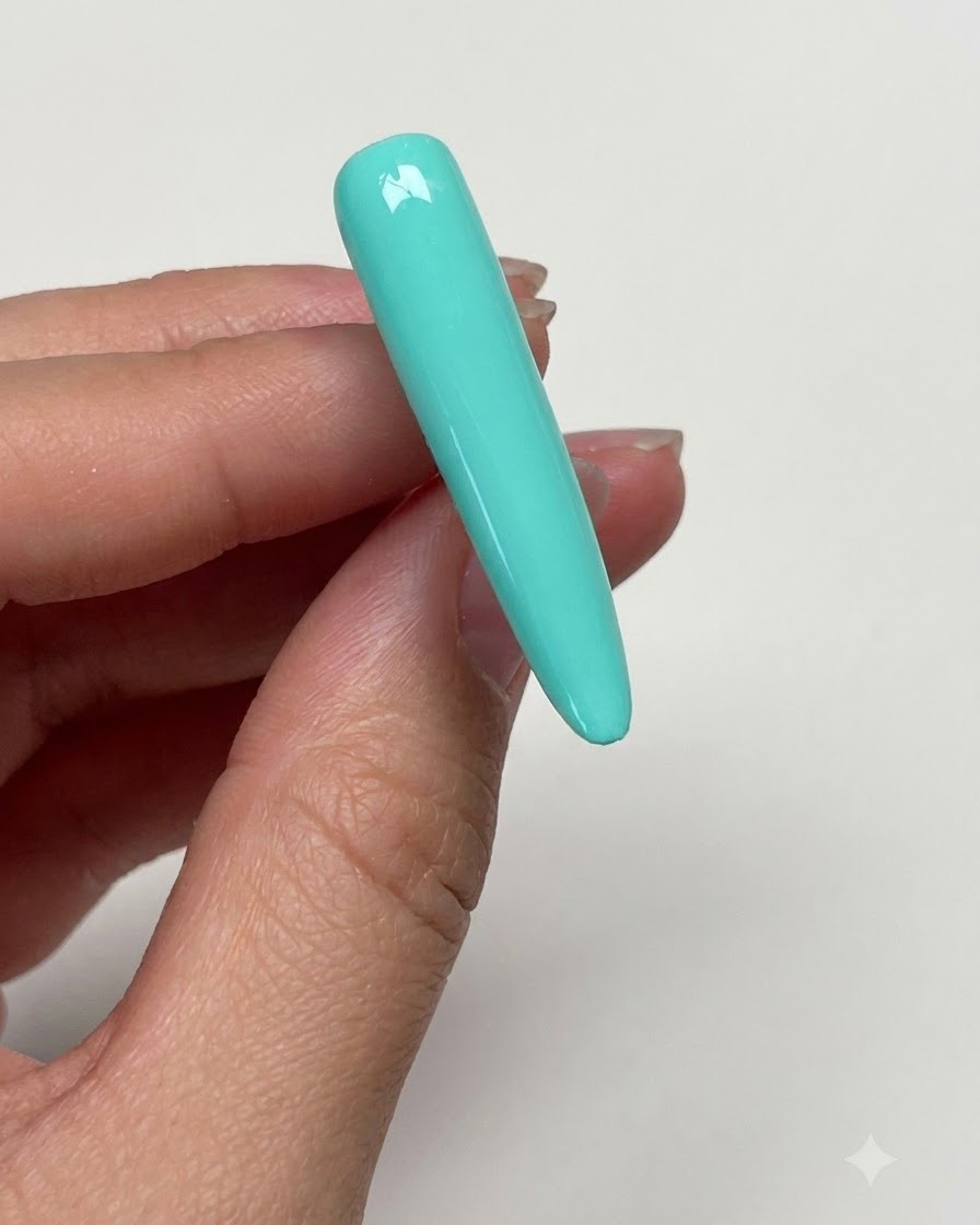 A hand wiping the cured mint green nail surface with an alcohol pad to remove tackiness.