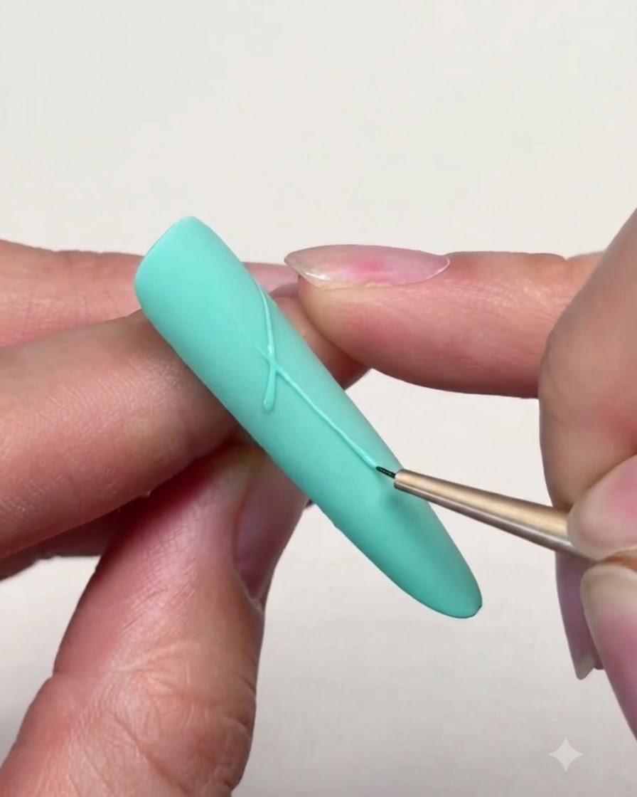 A fine liner brush drawing precise lines to connect star points on a mint green nail.