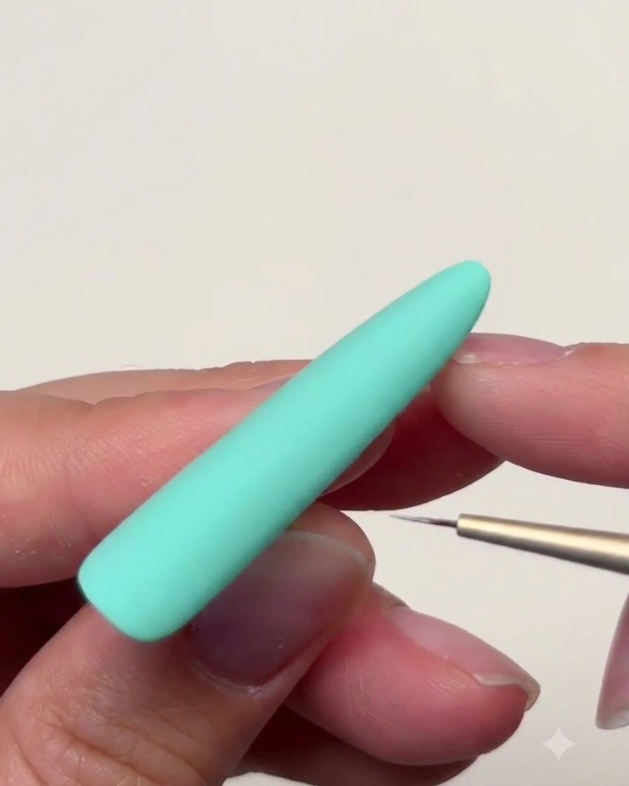 A close-up view of a mint green nail surface while tapering star tips outward with a brush.
