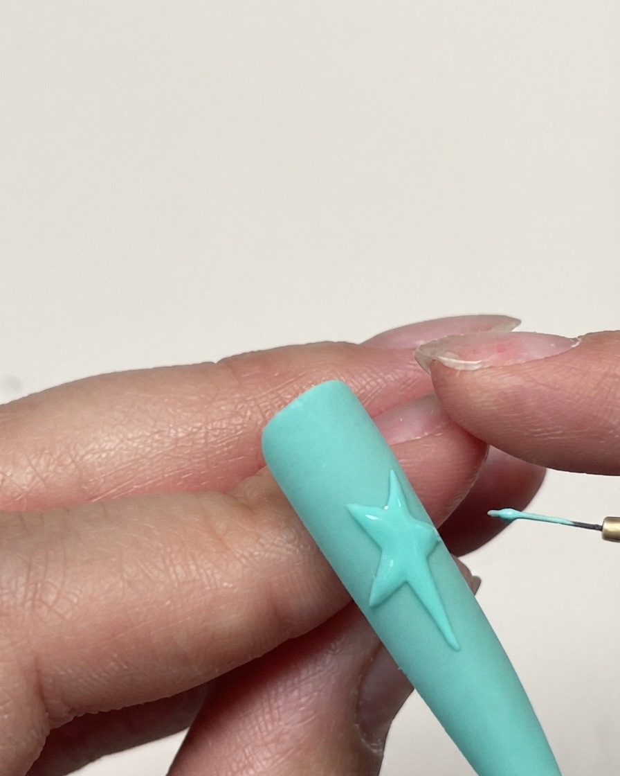A detailed shot of a completed gel star outline on a mint green nail before texture application.