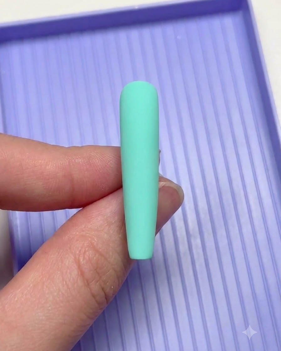 A hand holding a mint green nail over a purple sorting tray during nail art.