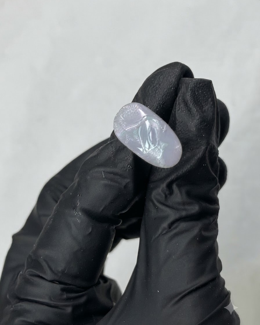 A metal tool scooping transparent M01 building gel from the interior of a jar.