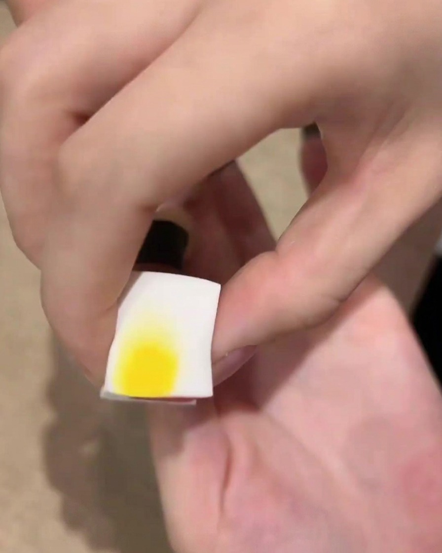 A white cosmetic sponge holding black gel polish near a fingernail, ready to dab an ombre effect.
