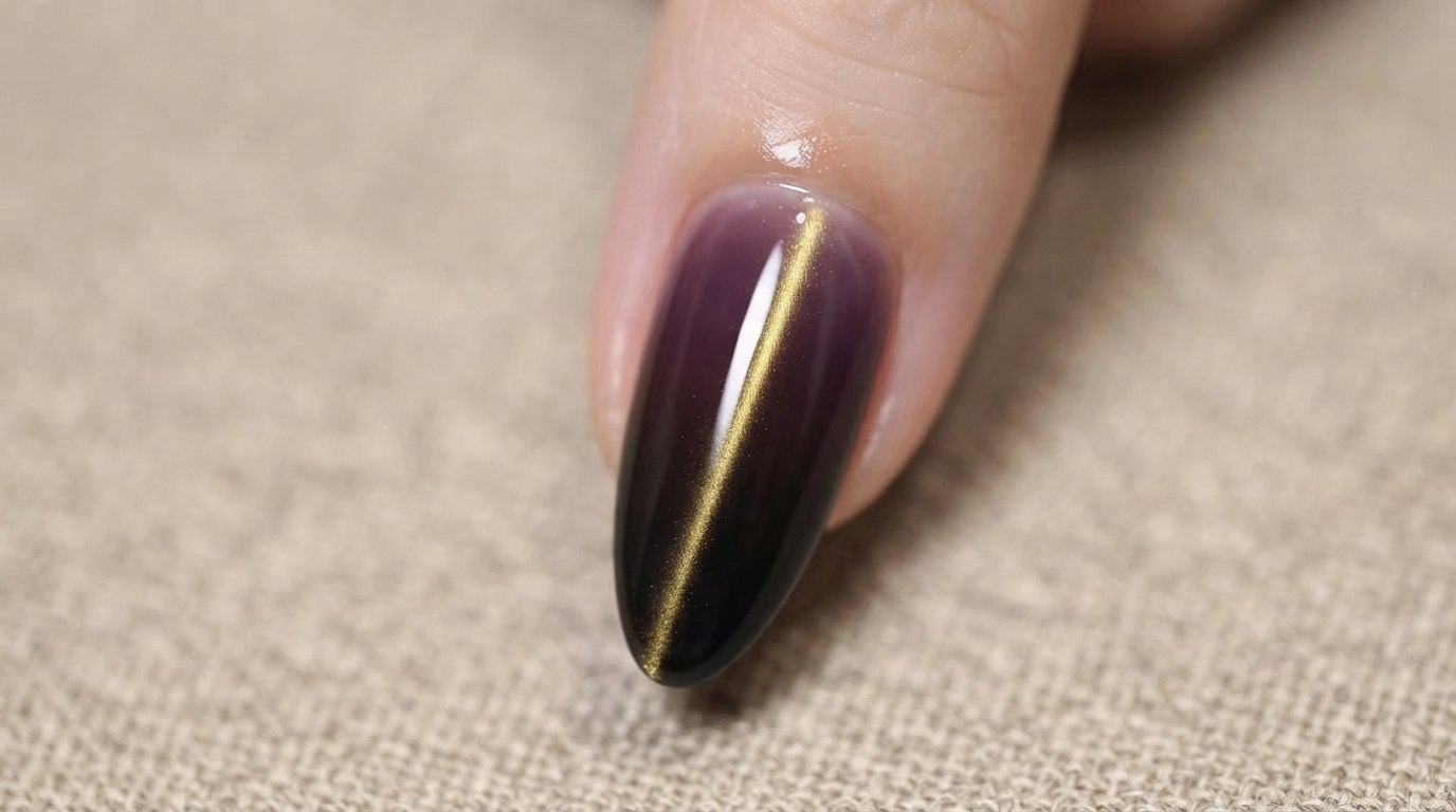 A close-up view of the finished dark purple and black ombre nail with a gold cat-eye stripe on a models arm, showcasing the glossy gothic aesthetic.