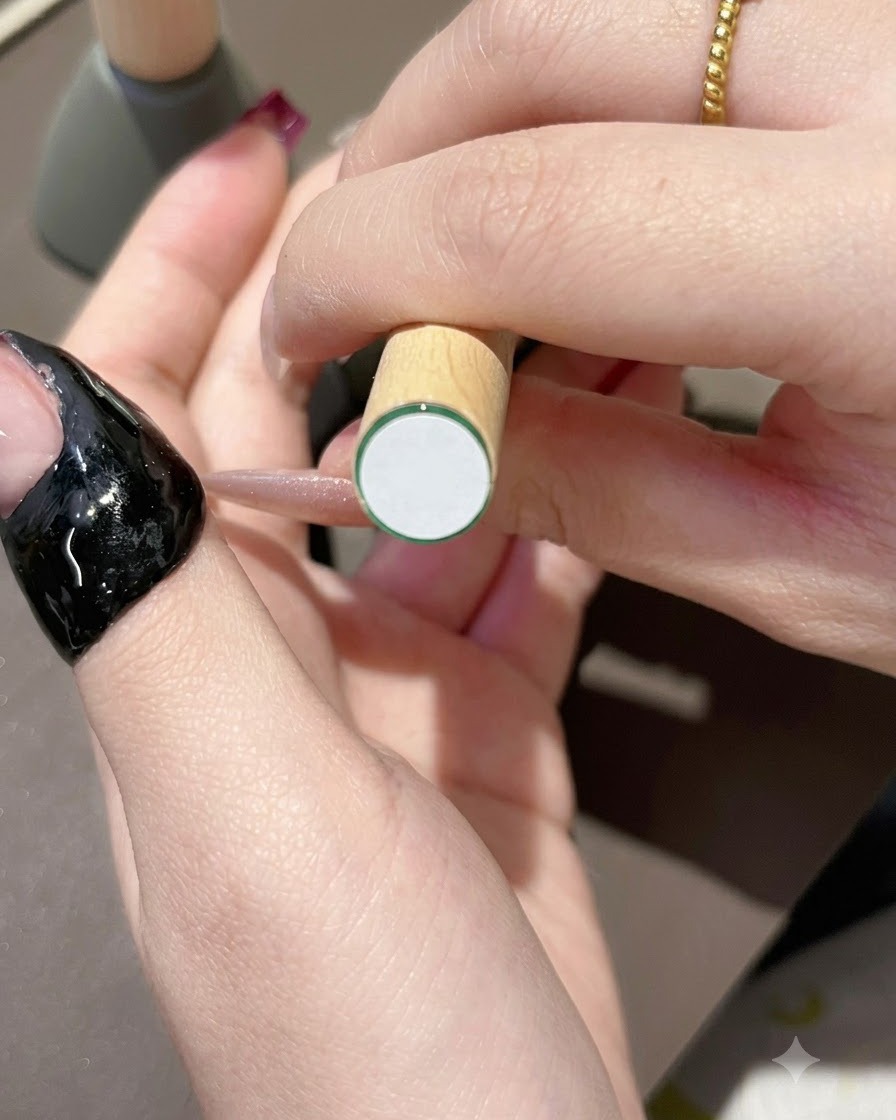 A brush applying dark purple gel polish onto the tip of a natural-looking nail.