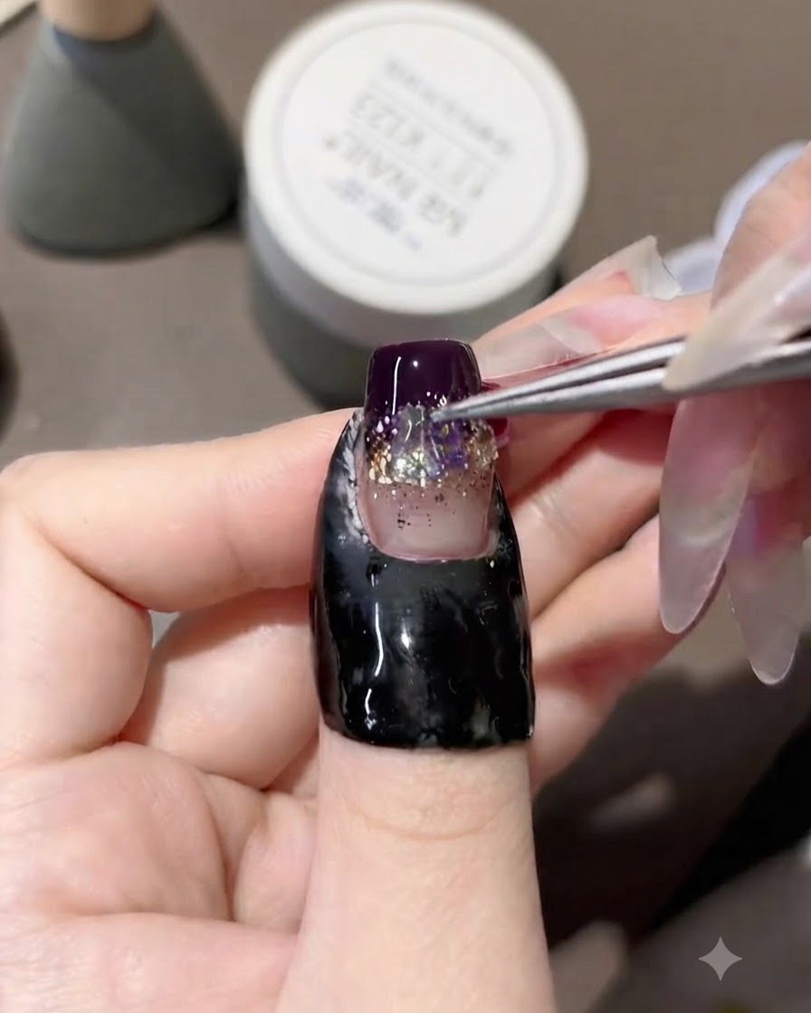 A pair of tweezers placing iridescent aurora rhinestones down the center of a decorated gel nail.