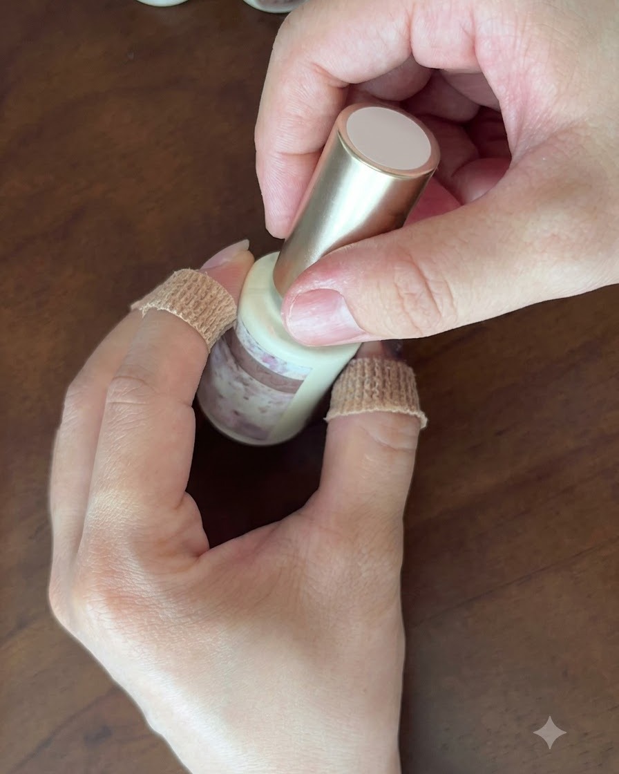 Two hands holding a closed bottle of light pink cat-eye gel polish.