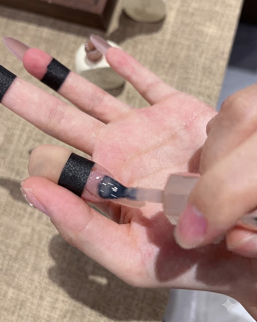 A nail brush applying purple cat-eye gel to the tip of a nail for an ombre effect.