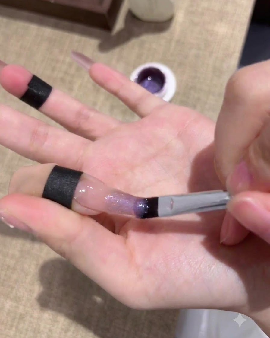 Nails curing under a UV/LED lamp after applying the first layer of purple cat-eye gel.
