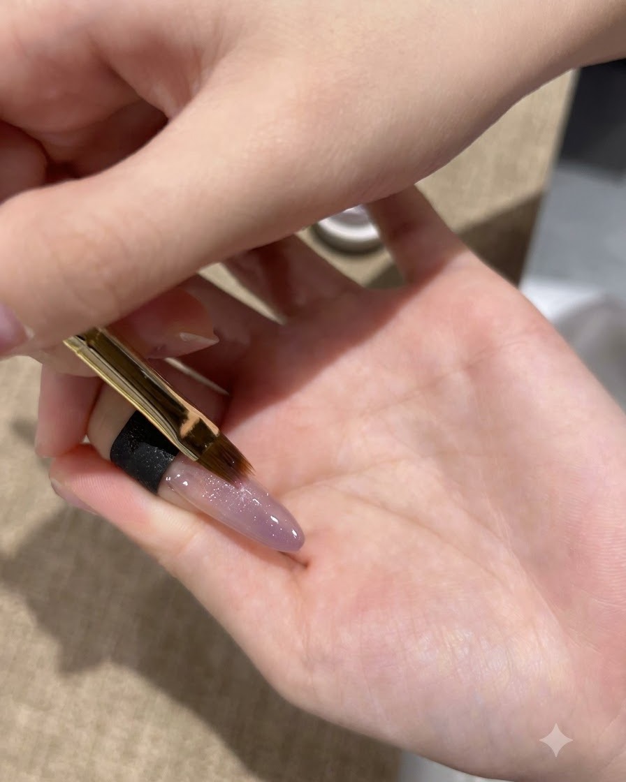 A fine brush applying a second layer of purple cat-eye gel onto the nail tip.