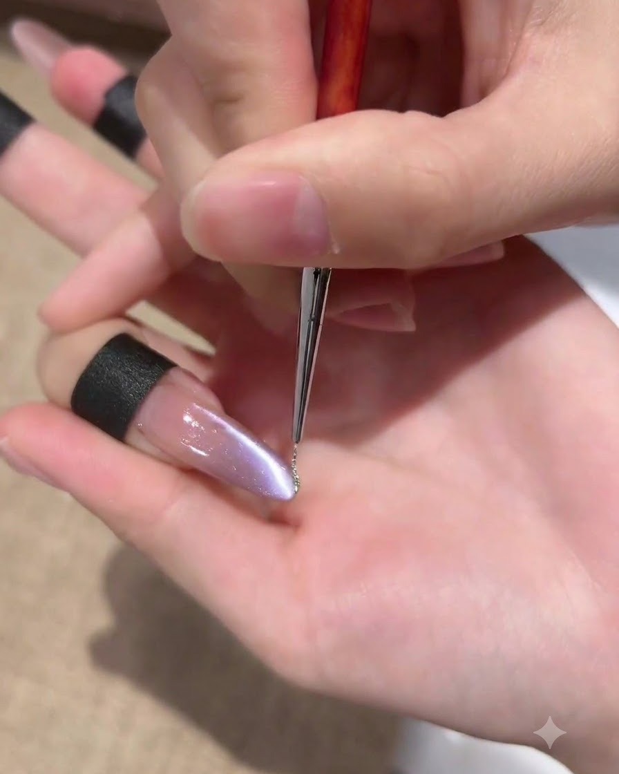 A fine liner brush applying a very thin line of sparkling silver gel along the sidewall of a purple cat-eye nail.