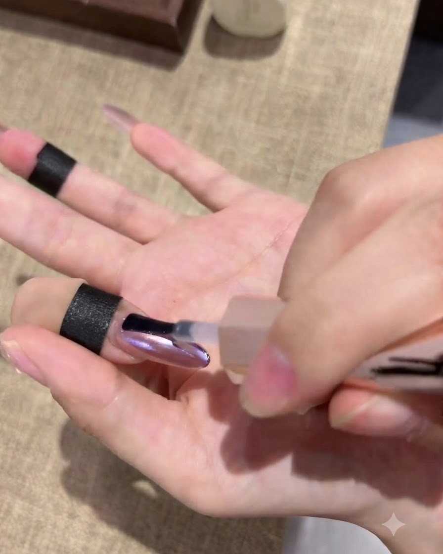 A hand resting inside a nail curing lamp with the fingertips illuminated under light.