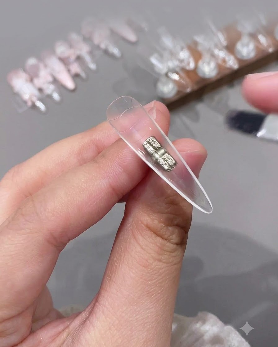 A small brush applying a clear top coat to the inside hollow section of a clear artificial nail tip.