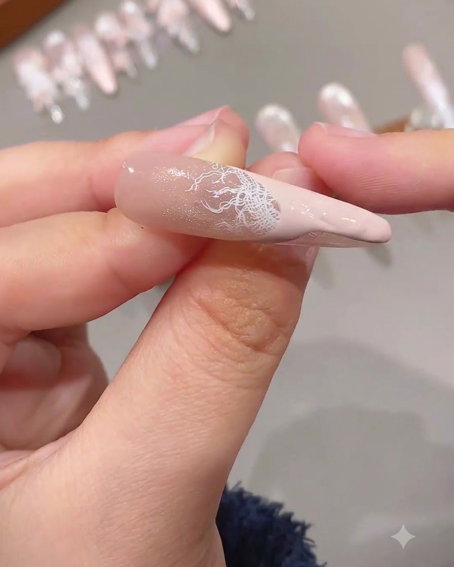 A completed French tip featuring an intricate white lace overlay combined with a solid pink colored tip on an extended nail.