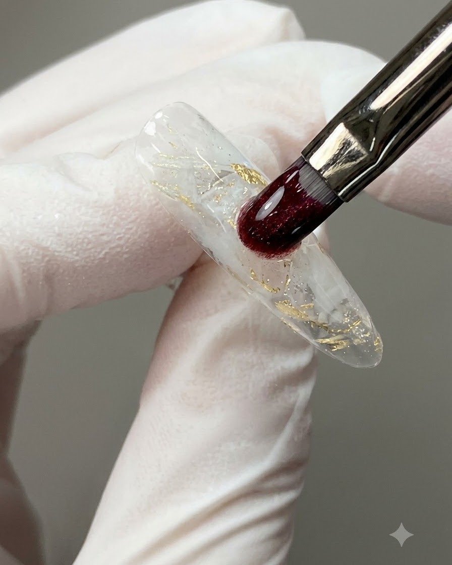A nail brush applying a clear leveling bead of construction gel over a decorated nail surface.