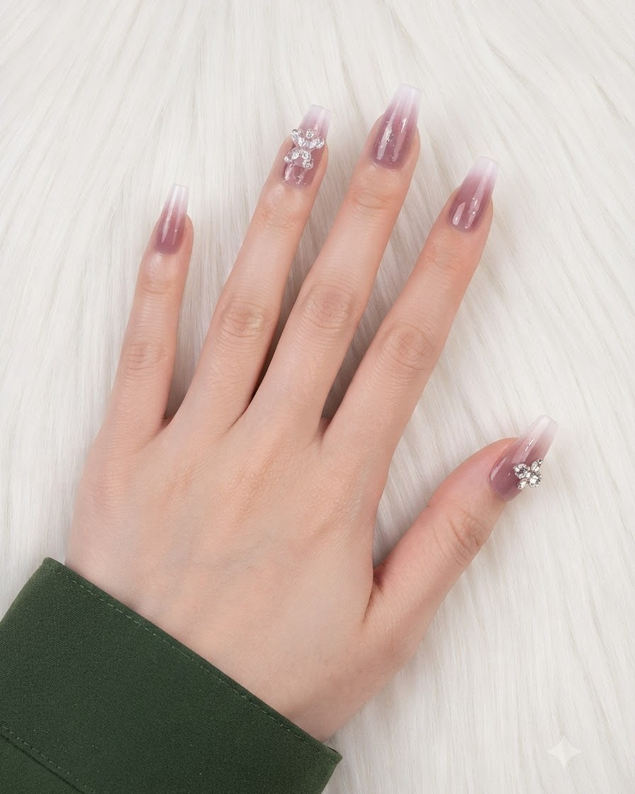 A hand with finished gradient nails and charms placed on the ring finger and thumb.
