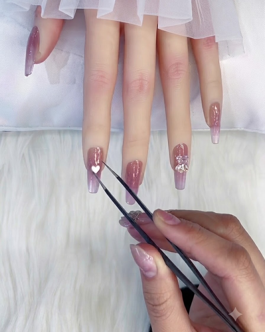 A pair of fine metal tweezers holding a small white heart-shaped embellishment directly above the nail of an index finger.