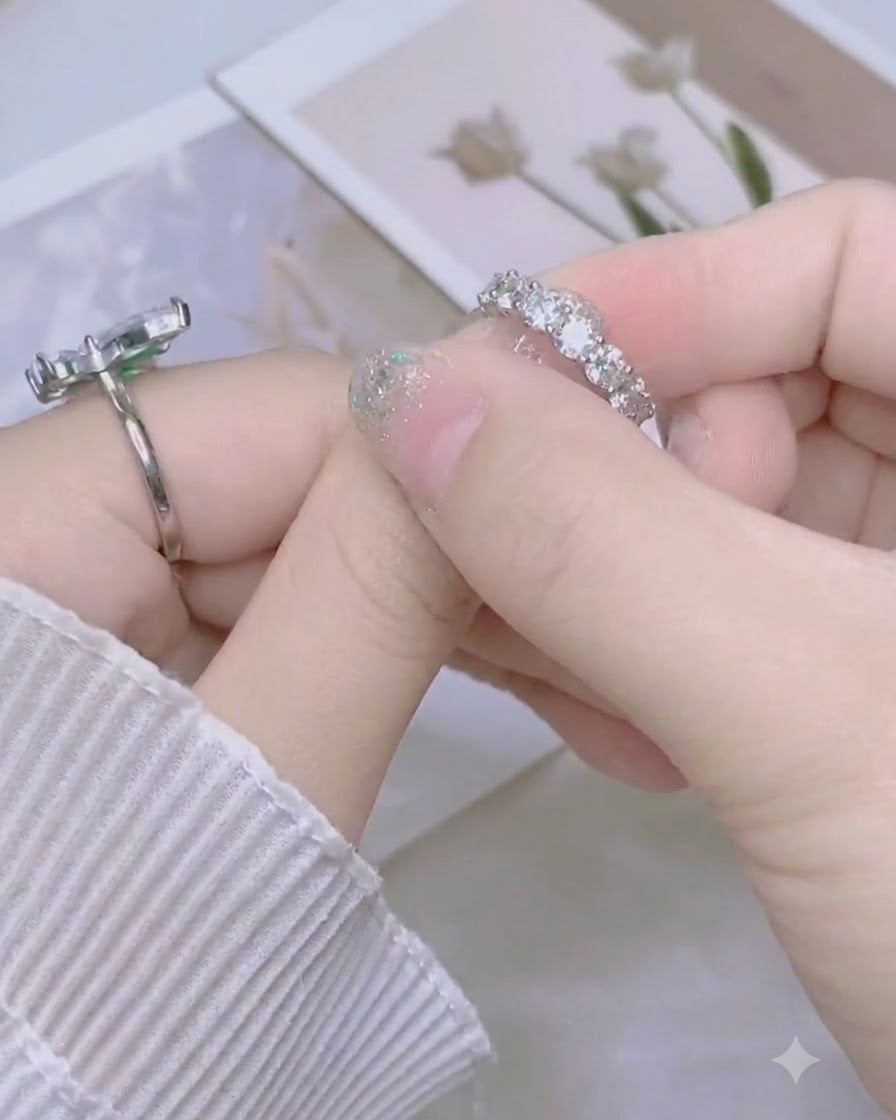 Fingers pinching the excess silver glitter nail sticker at the tip of the thumb nail.