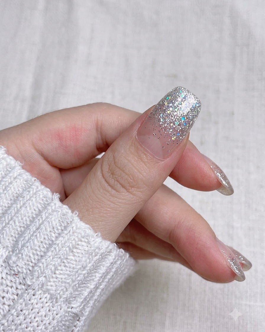 A close-up view trimming the extra nail wrap strip along the tip with small manicure scissors.