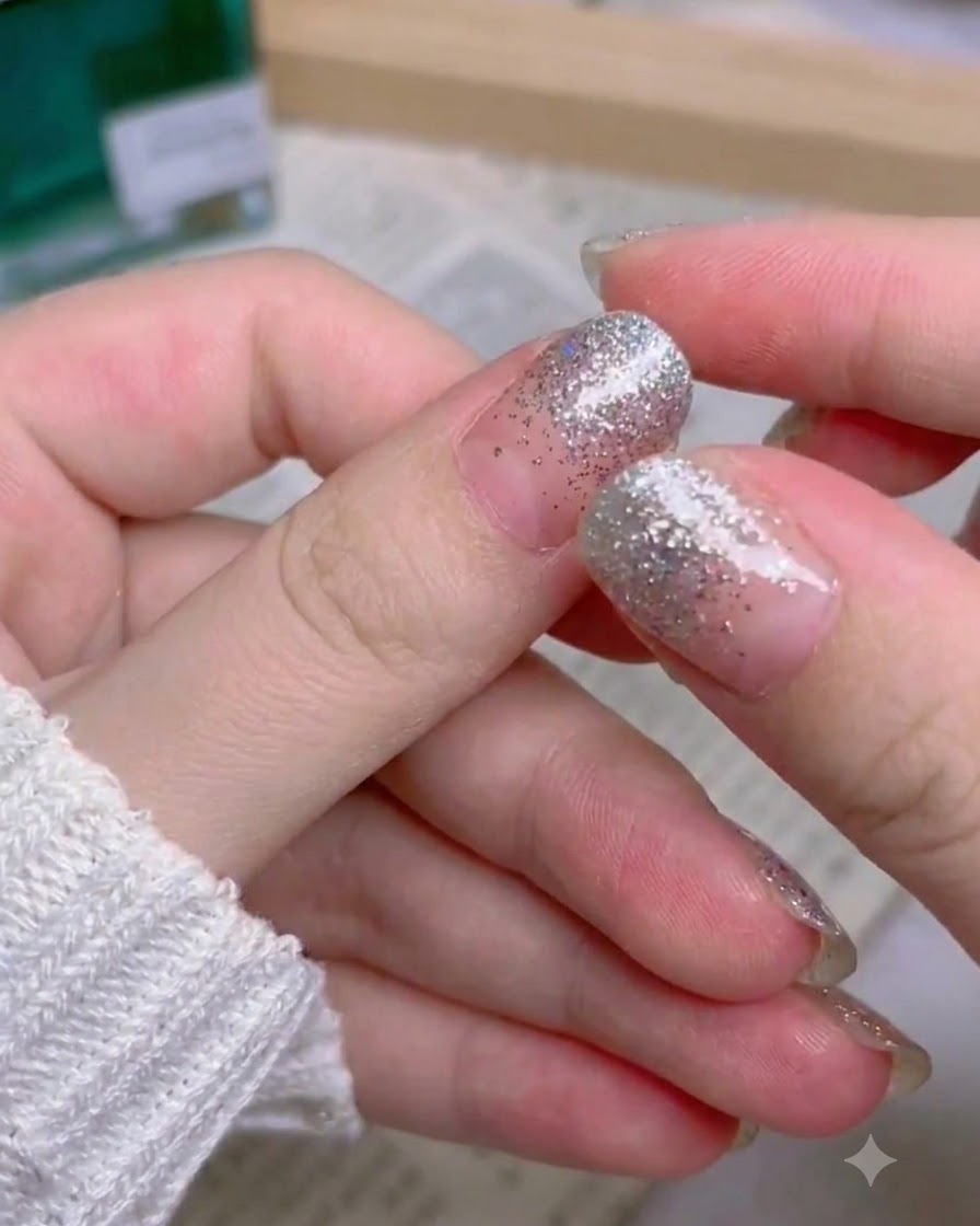 A hand showing the completed full set of silver glitter gradient press-on nails.