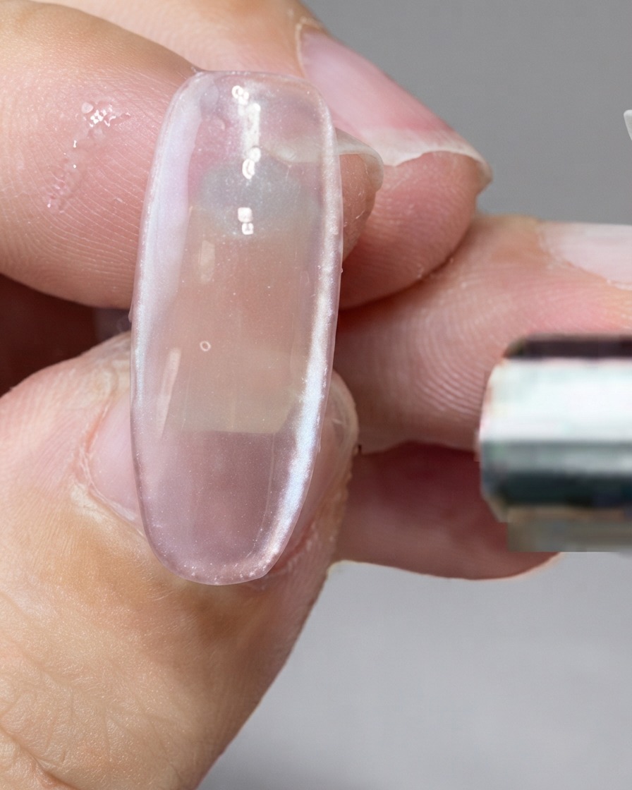 A bar magnet holding magnetic particles along the right side of a nail.