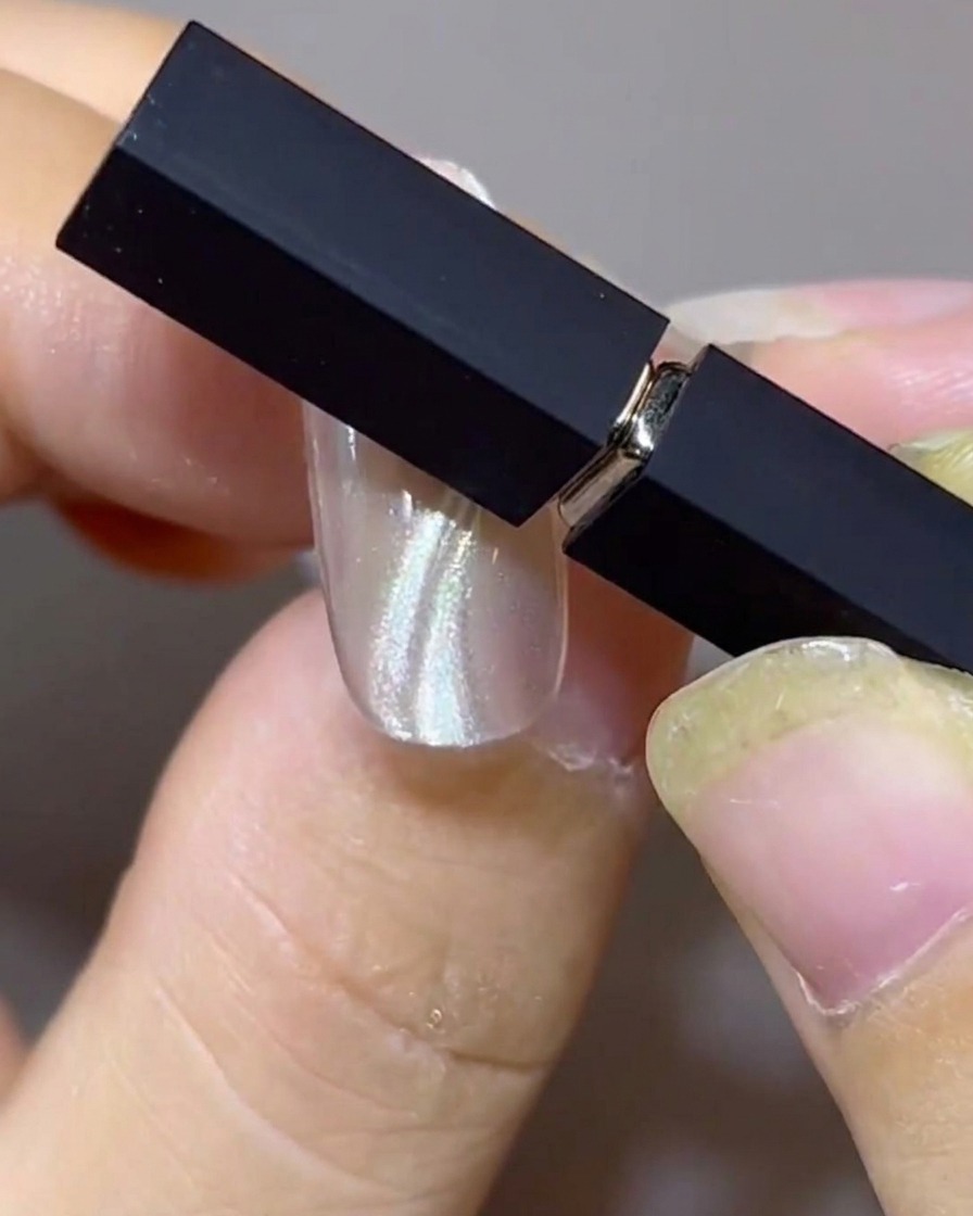 Two magnets positioned at an angle over a nail to shape parallel double floating cat-eye bands.