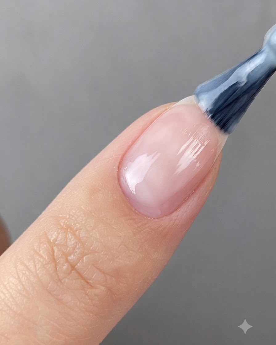A nail brush applying translucent white gel onto a prepped fingernail.