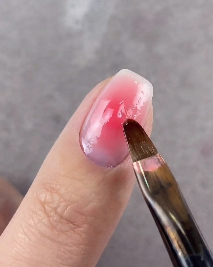 A round-headed brush blurring the edges of the center dot on a nail.
