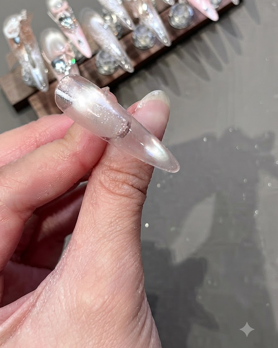 A cleaning wipe being used to wipe down the surface of a cured nail on a display stand.