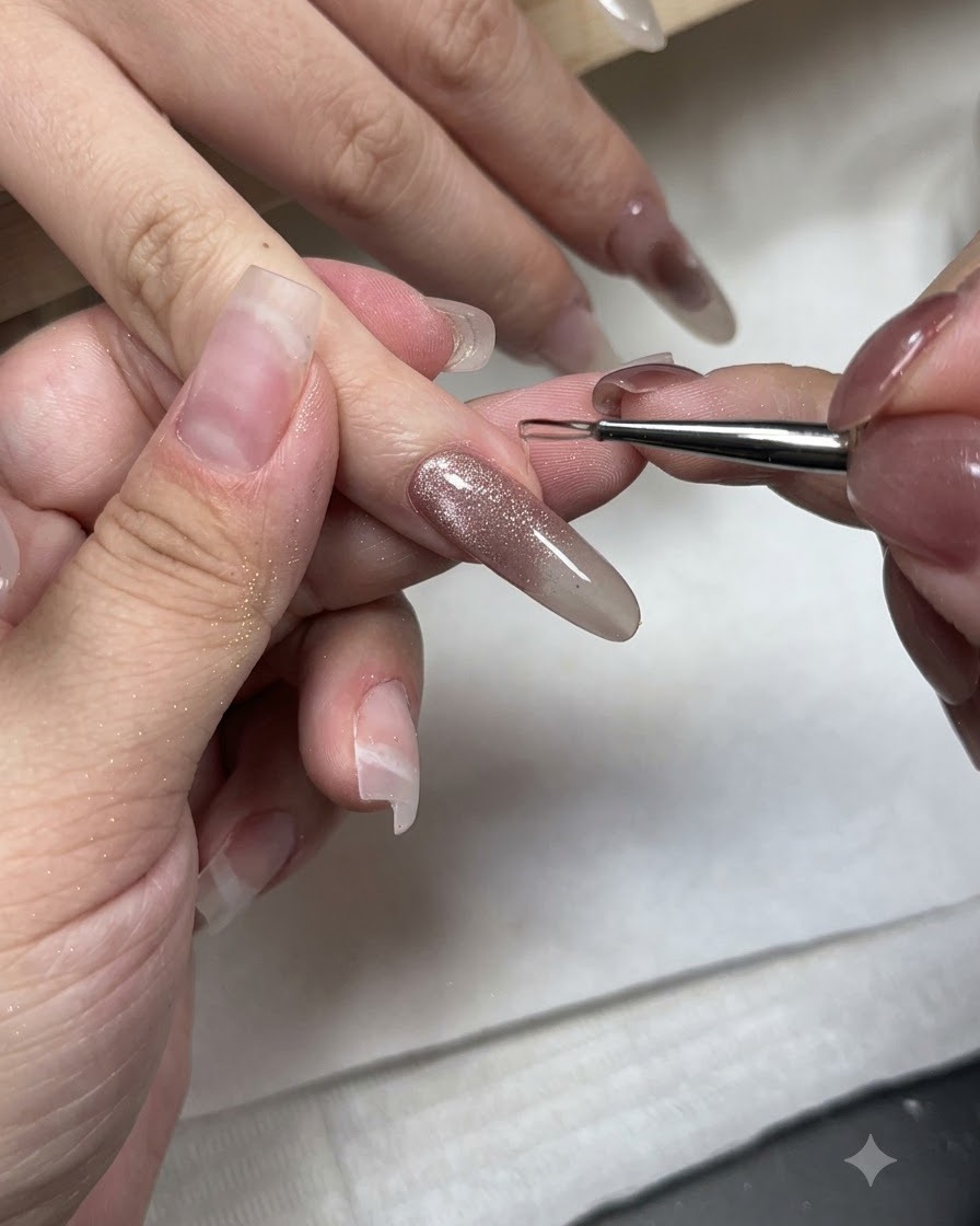 A fine nail art brush applying non-wipe styling gel to the tip of a cat-eye gel nail.