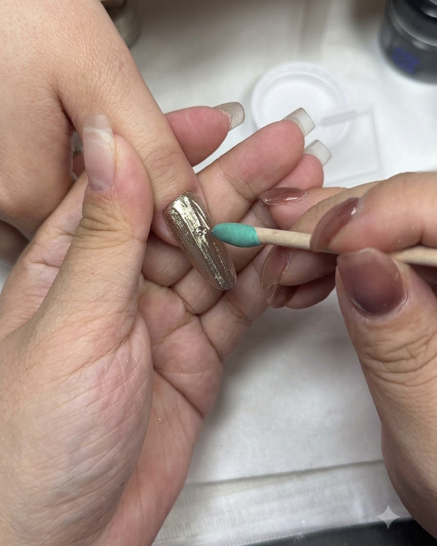 A manicure brush applying top coat over a chrome-finished nail surface.