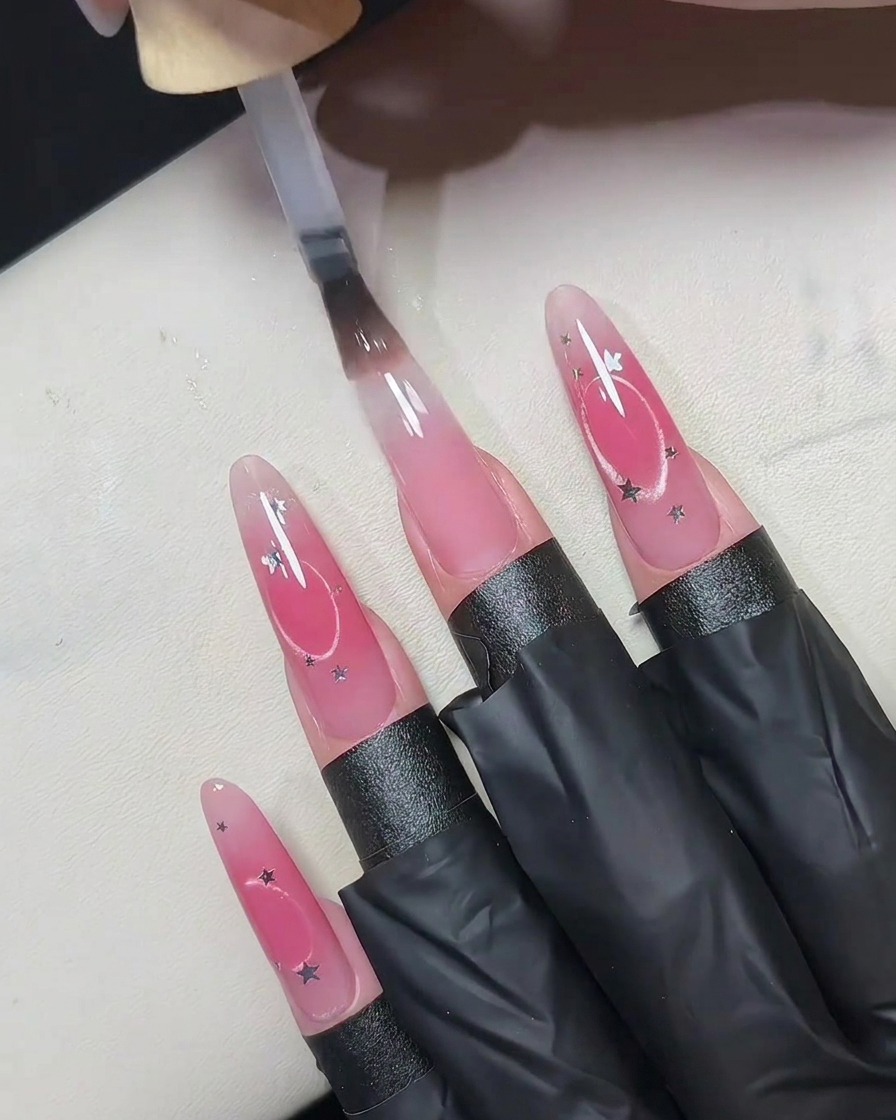 A small handheld UV LED lamp held closely over artificial nails to cure the top layer.