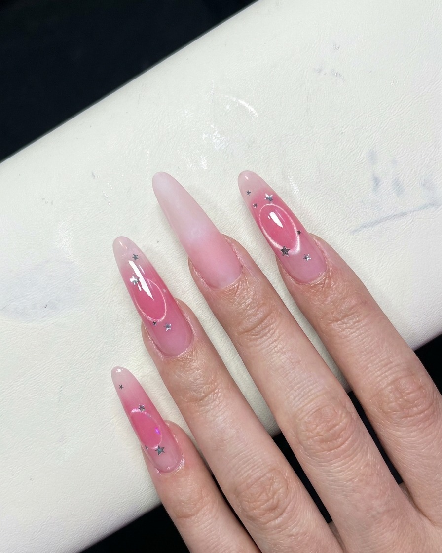 A close-up view of fingers showing a gradient pink blush effect on the center of the nails.